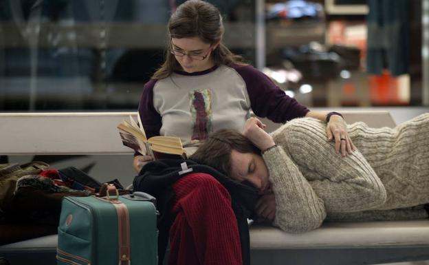Un chico reposa sobre las piernas de su pareja en la sala de espera de un aeropuerto. /Luis Ángel Gómez