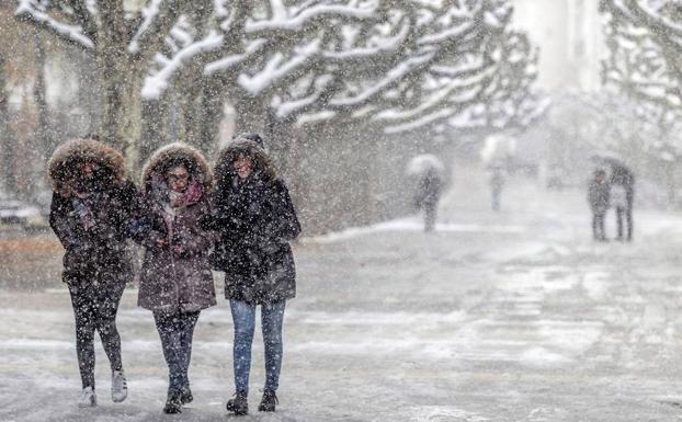 Varias personas caminan por Burgos en medio de una intensa nevada. /Santi Otero-EFE