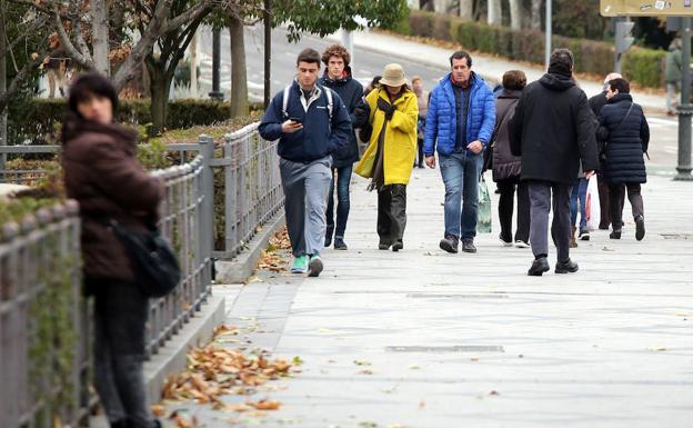 Varias personas se protegen del viento y del frío ante la previsión de fuertes rachas de viento a lo largo del día/