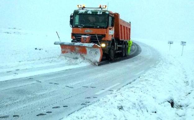 Una máquina quitanieves trata de despejar la carretera./