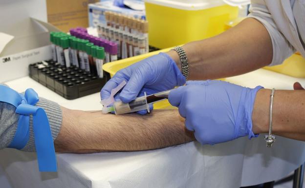 Una enfermera extrae sangre a un paciente./
