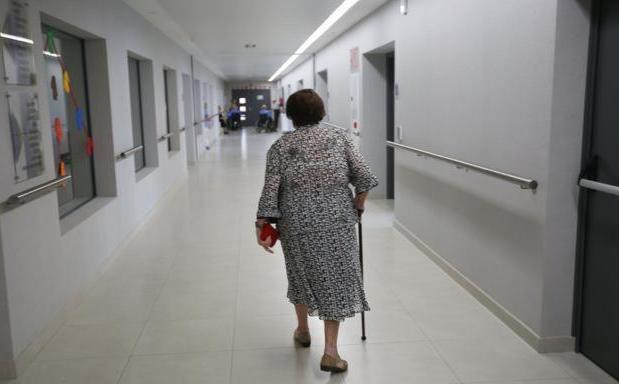 Una anciana camina con un bastón./