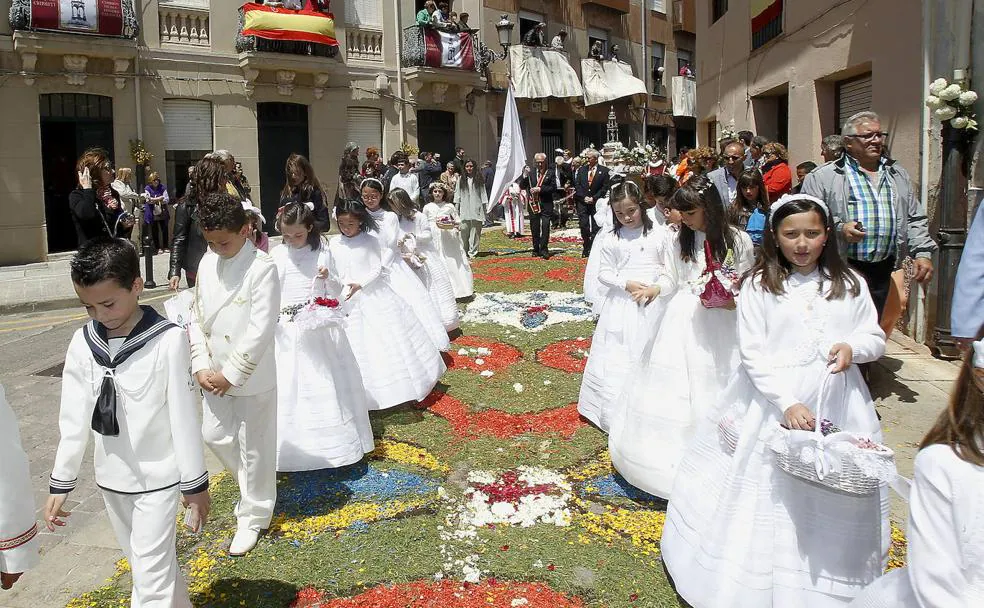 Niños y niñas de Primera Comunión preceden al Santísimo sobre las alfombras de flores durante la procesión del Corpus Christi en Carrión./