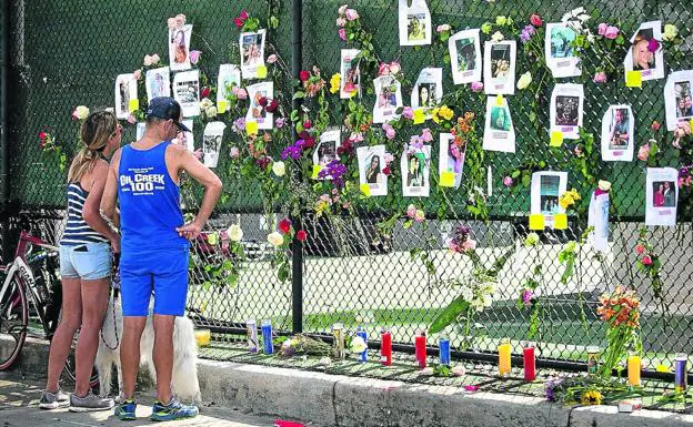 Allegados de los desaparecidos han colocado sus fotos en una valla, donde han depositado velas y flores en su honor./afp