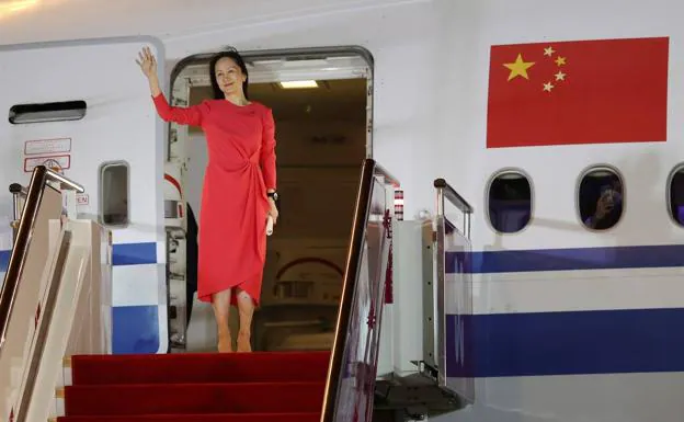 Meng Wanzhou saluda desde la puerta del avión, este sábado, nada más aterrizar en el aeropuerto de Shenzhen. /EFE