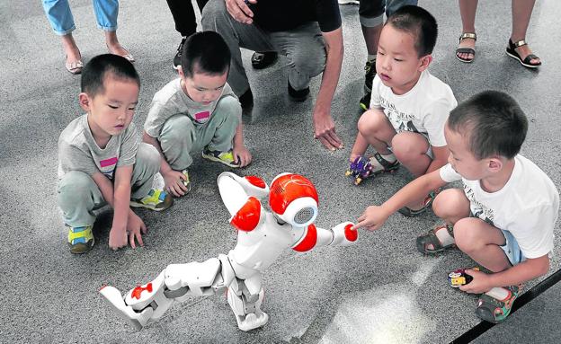 Un grupo de niños chinos juegan con un robot que hace taichí en Pekín/Jason Lee