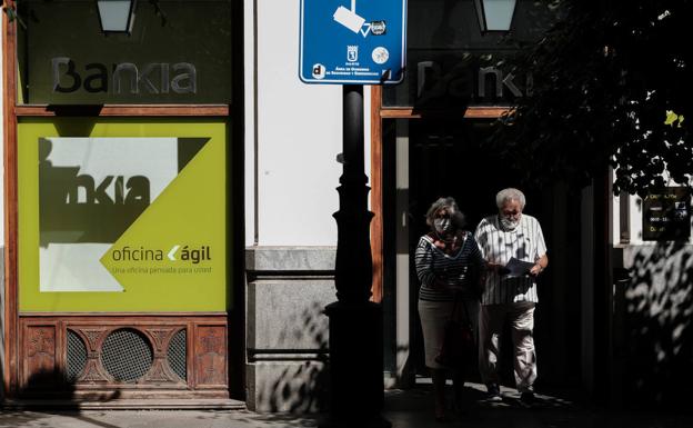Dos personas caminan junto a una sucursal bancaria en Madrid. /Óscar Chamorro