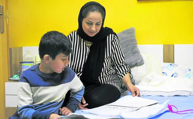 Deberes. Sohaila Omaryar ayuda a su hijo Amir con las tareas del colegio.