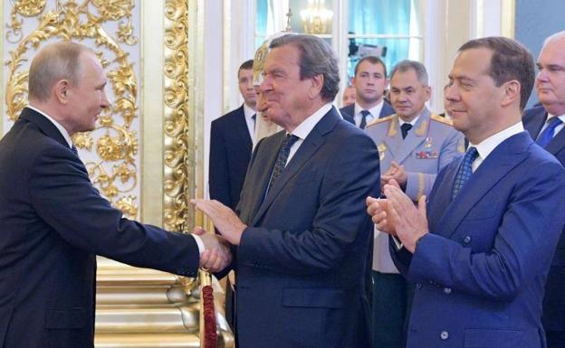 Wladimir Putin schüttelt dem ehemaligen deutschen Bundeskanzler und sozialdemokratischen Führer Gerhard Schröeder in Anwesenheit des russischen Ministerpräsidenten Dmitri Medwedew im Jahr 2018 die Hand / Alexey DRUZHININ / AFP